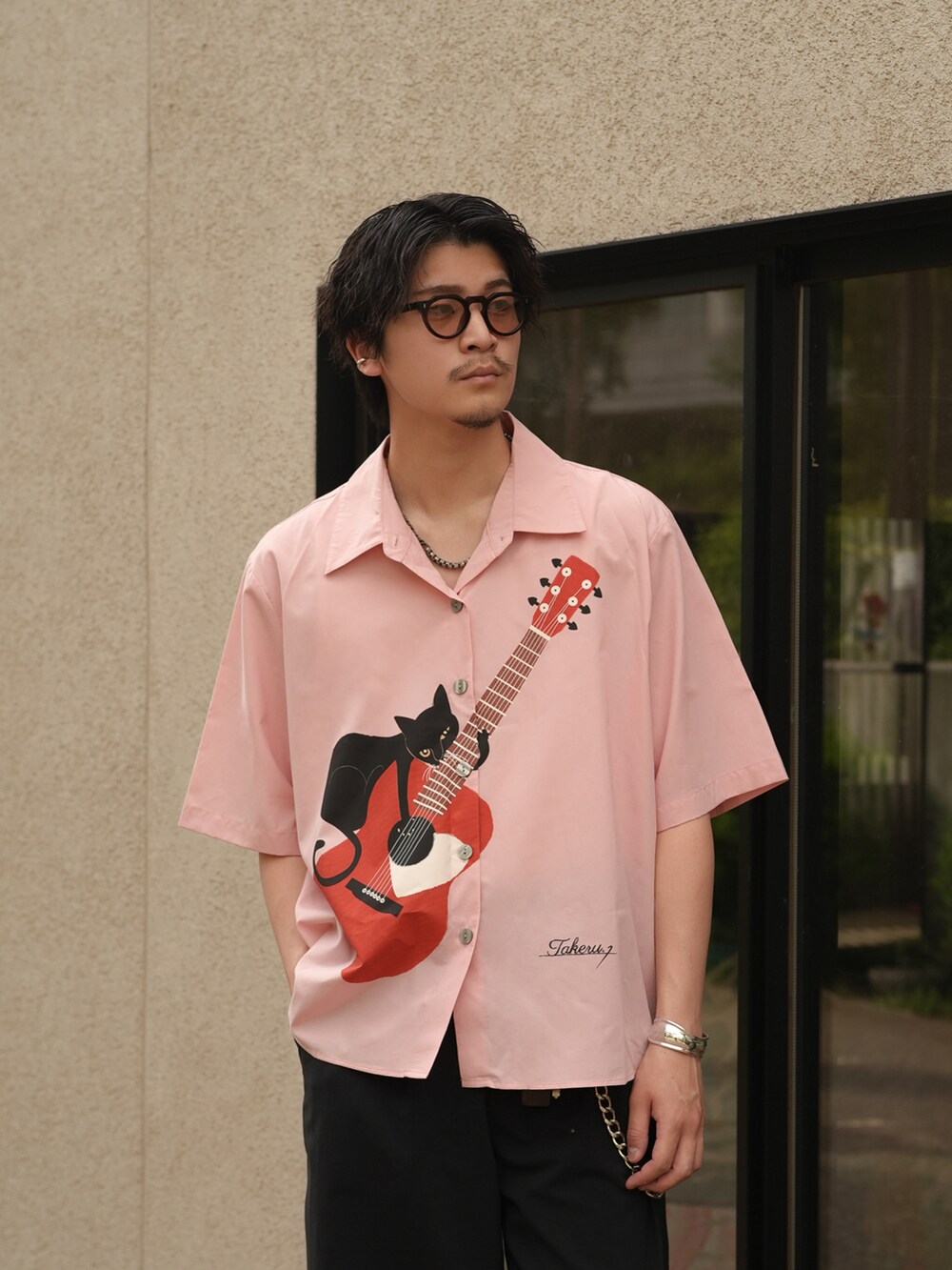 ブラック系のスラックス、ブラック系のスリッポン、ピンク系のシャツ/ブラウスを着用したメンズの夏コーディネートの2枚目の写真