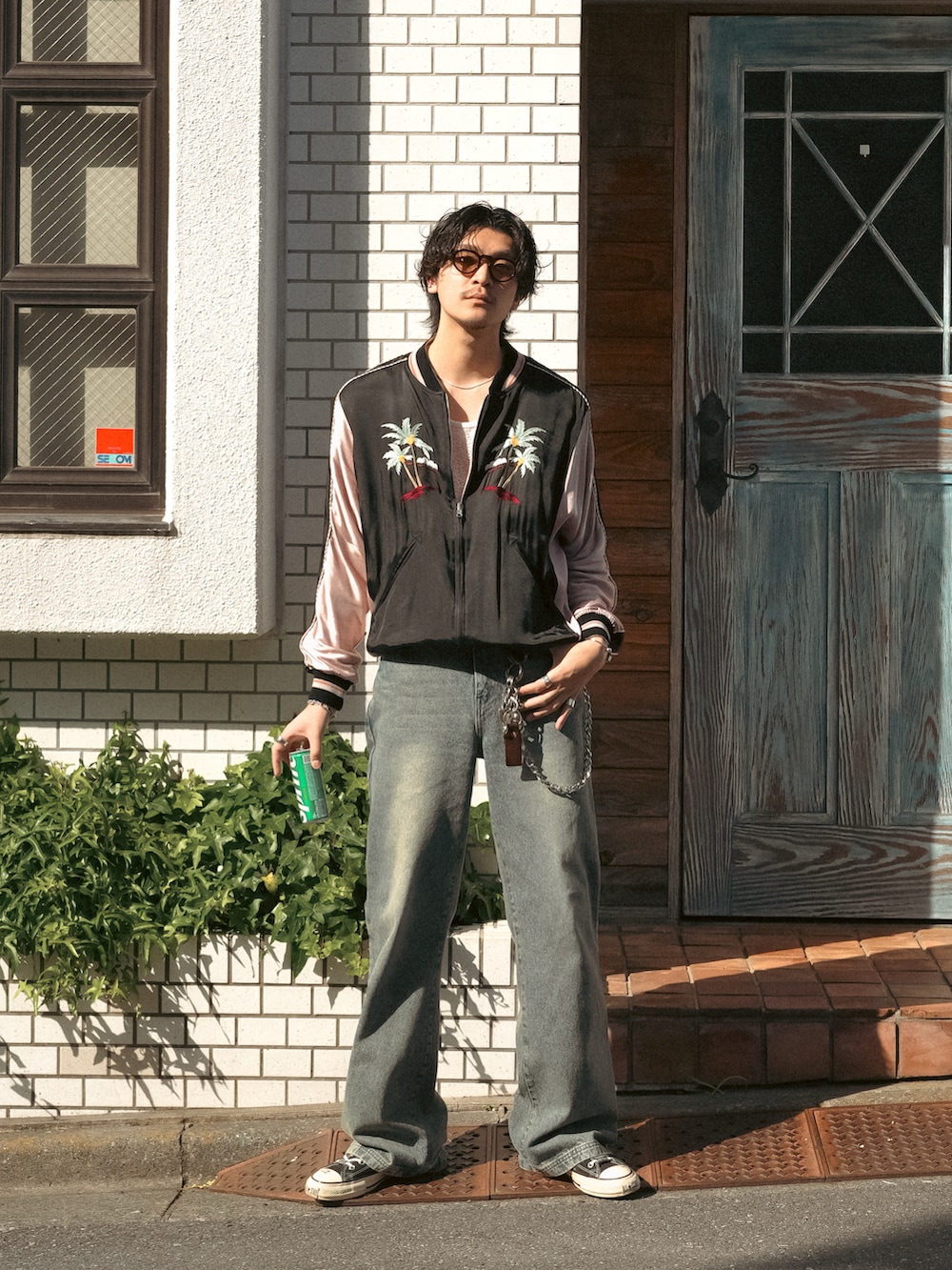 ブルー系のデニムパンツ、ブラック系のスニーカー、ブラック系のスタジャンを着用したメンズの春コーディネートの3枚目の写真