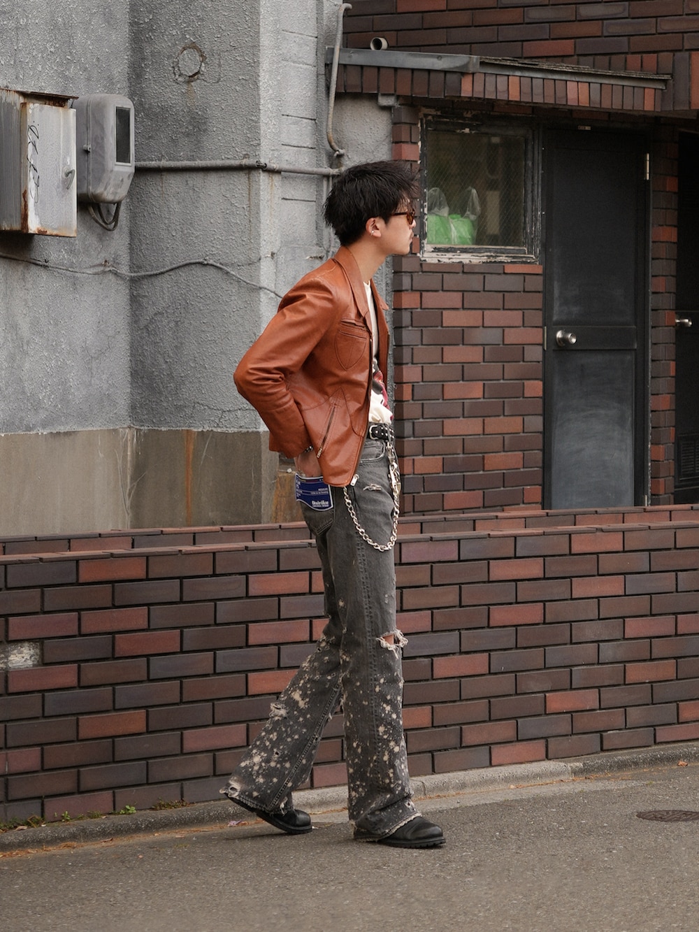 ブラック系のデニムパンツ、ベージュ系のTシャツ/カットソー、オレンジ系のジャケット/アウターを着用したメンズの春コーディネートの3枚目の写真