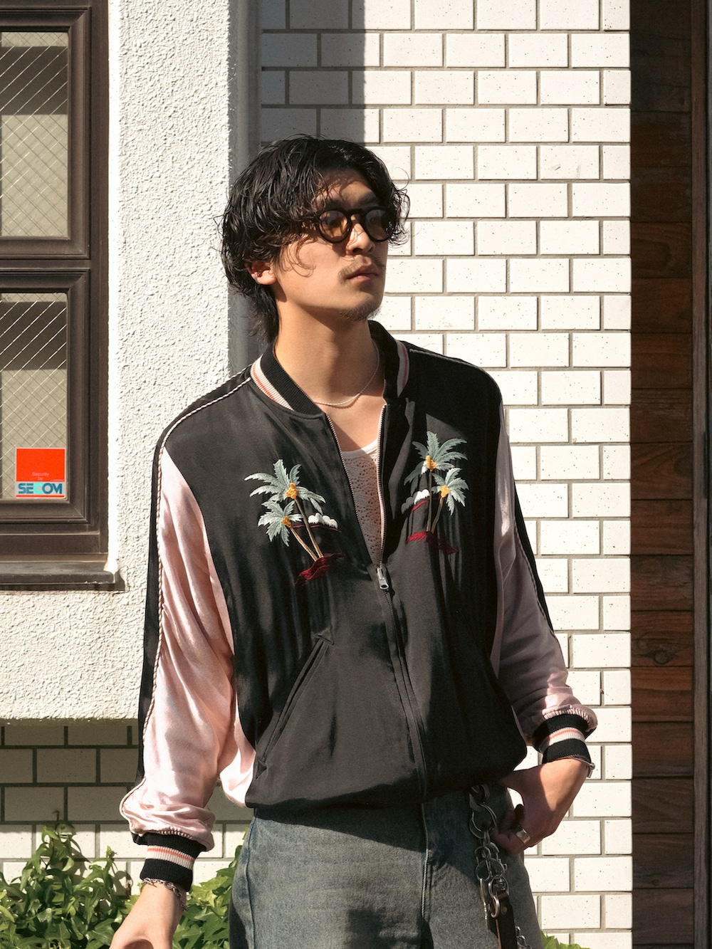 ブルー系のデニムパンツ、ブラック系のスニーカー、ブラック系のスタジャンを着用したメンズの春コーディネートの2枚目の写真