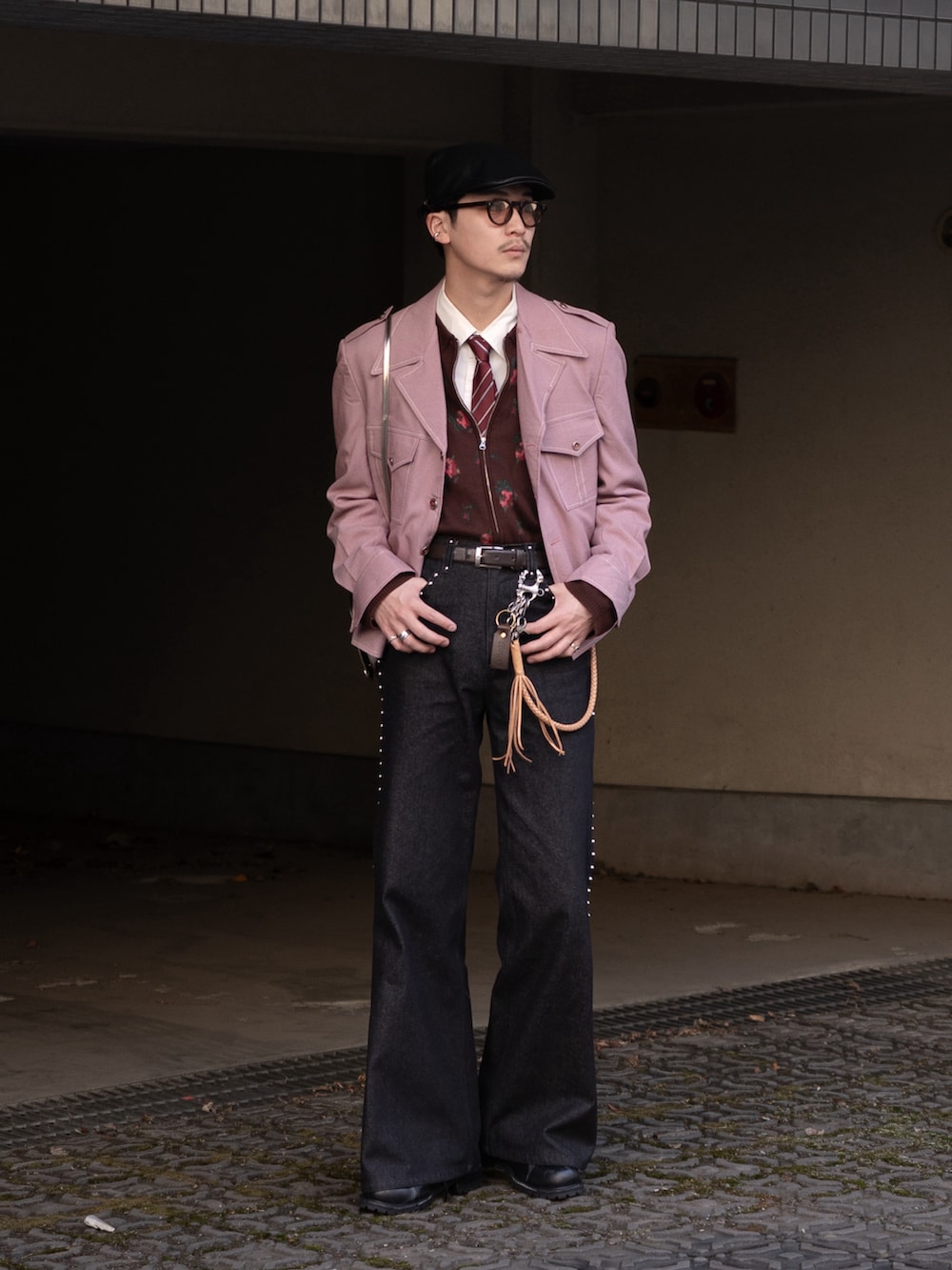 ブラック系のデニムパンツ、ピンク系のミリタリージャケット、ブラウン系のニット/セーターを着用したメンズの春コーディネートの4枚目の写真