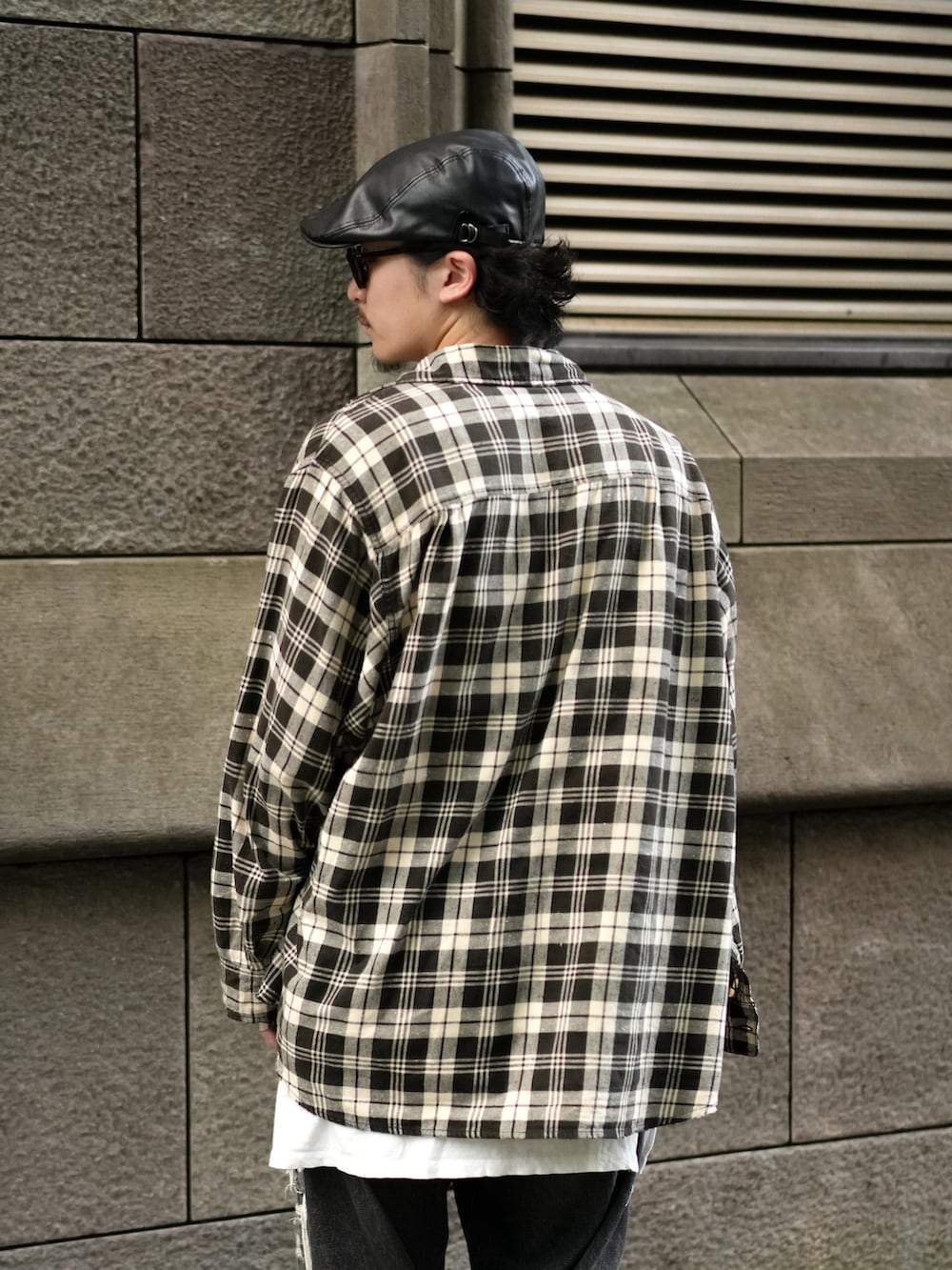 ブラック系のデニムパンツ、グレー系のスニーカー、ホワイト系のタンクトップを着用したメンズの秋コーディネートの4枚目の写真