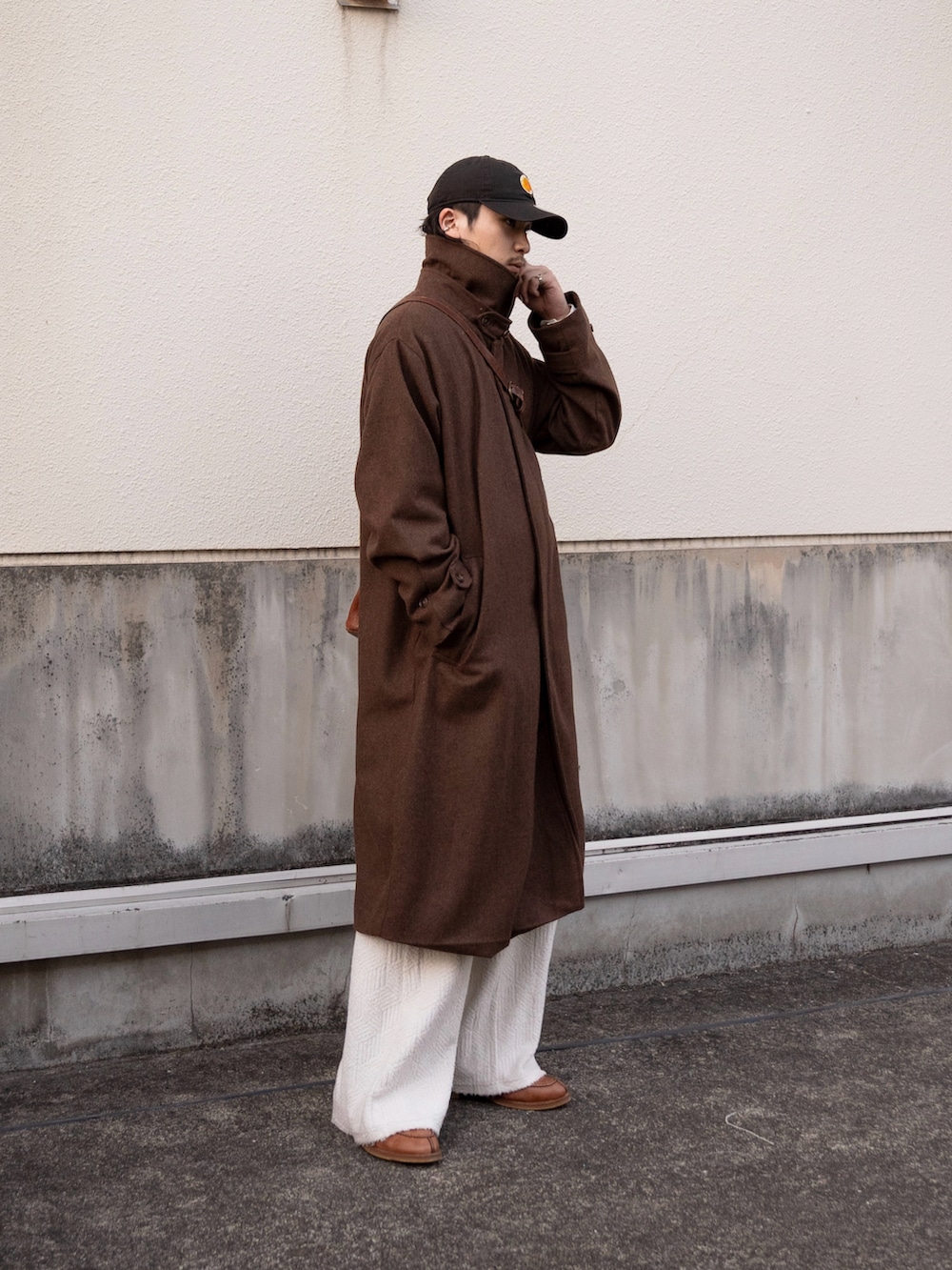 ブラウン系のステンカラーコート、ブラウン系のショルダーバッグ、ブラウン系のドレスシューズを着用したメンズの冬コーディネートの2枚目の写真