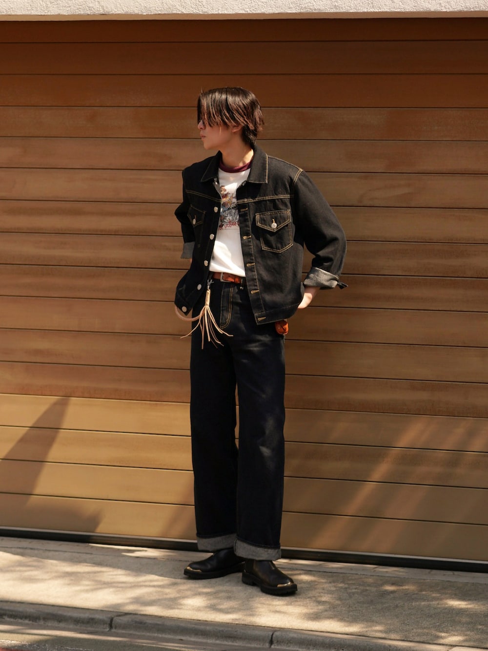 ブルー系のデニムパンツ、ブラック系のブーツ、レッド系のTシャツ/カットソーを着用したメンズの春コーディネートの2枚目の写真
