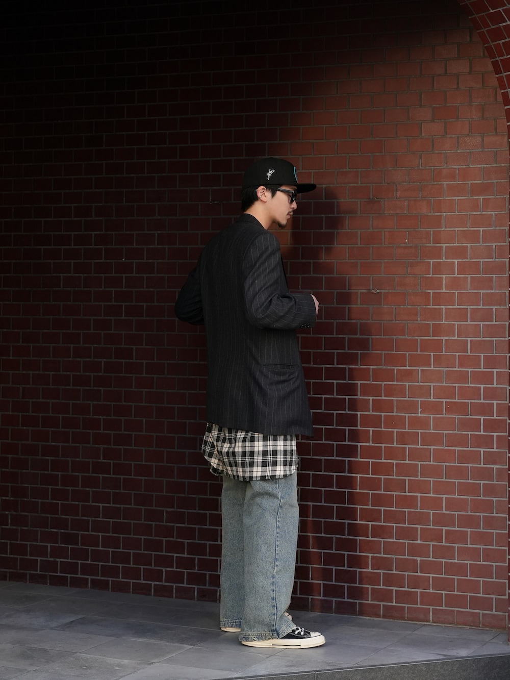 ブラック系のテーラードジャケット、ホワイト系のタンクトップ、ブルー系のデニムパンツを着用したメンズの冬コーディネートの3枚目の写真