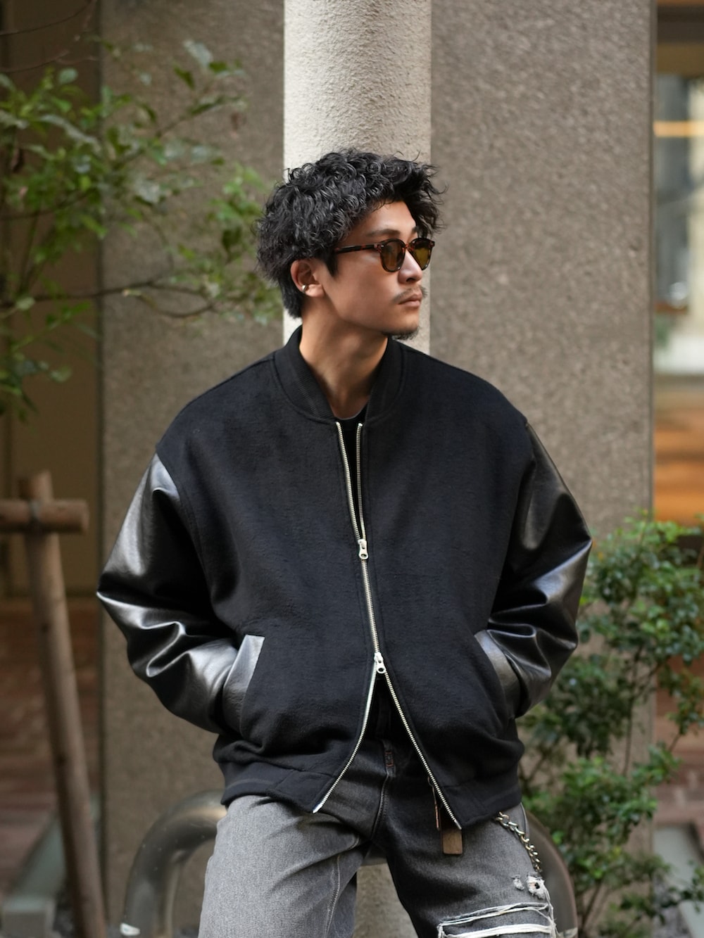 ブラック系のスタジャン、ブラック系のデニムパンツ、グレー系のスニーカーを着用したメンズの秋コーディネートの2枚目の写真