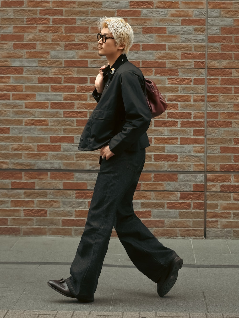 ブラック系のデニムパンツ、ブラウン系のローファー、ブラック系のブルゾンを着用したメンズの春コーディネートの3枚目の写真