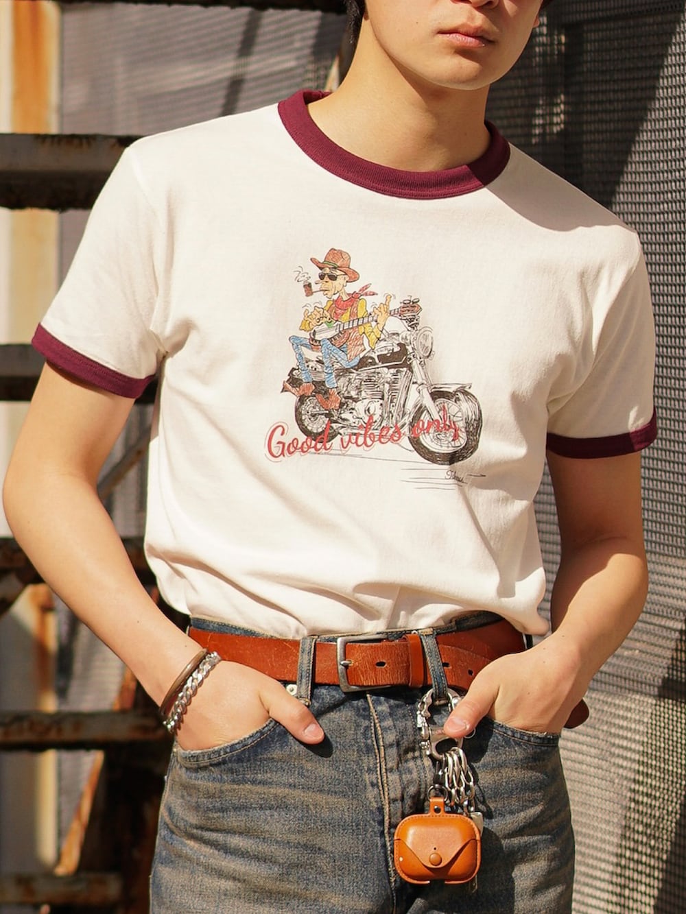 ブルー系のデニムパンツ、ブラック系のブーツ、レッド系のTシャツ/カットソーを着用したメンズの春コーディネートの5枚目の写真