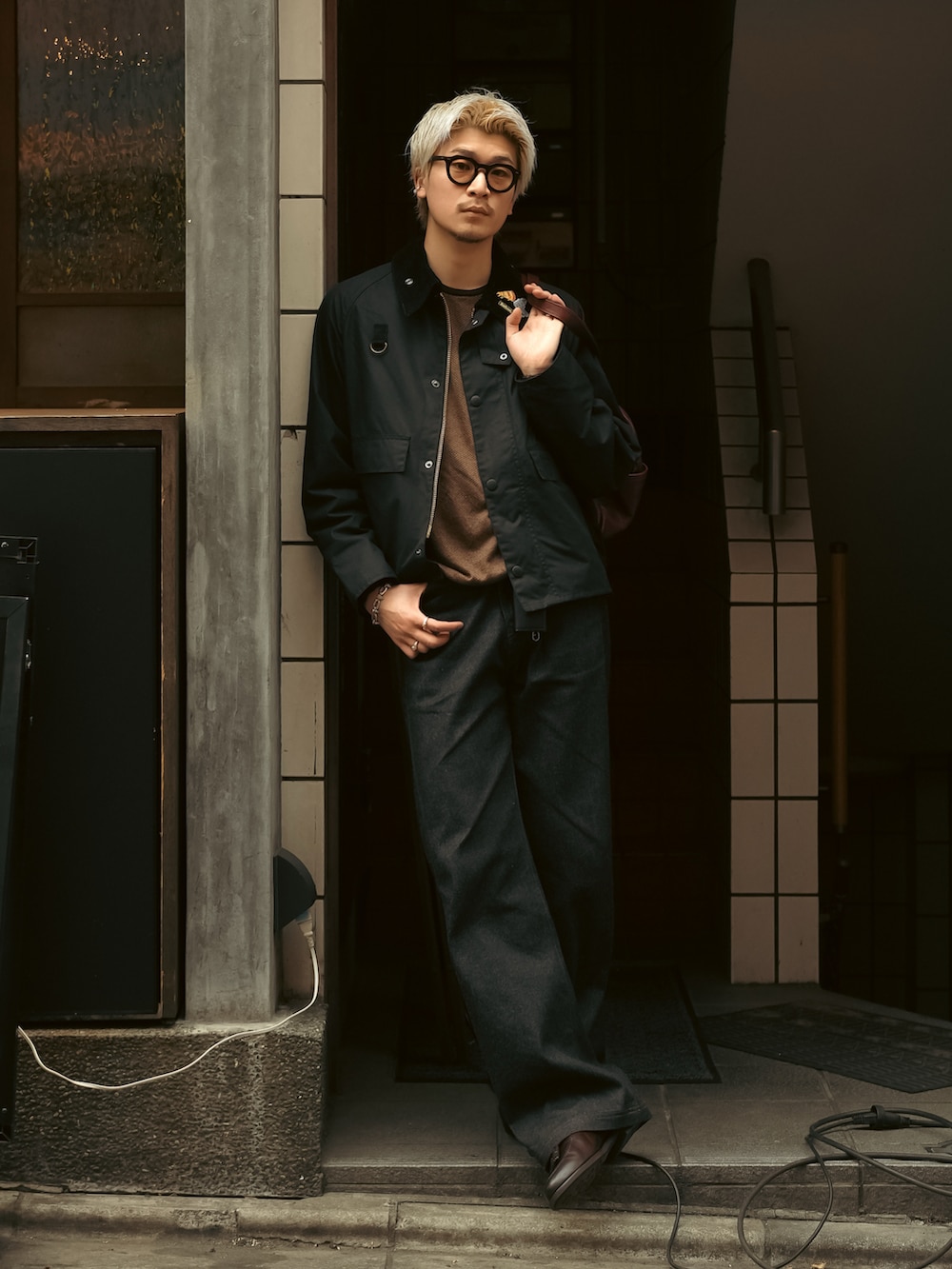 ブラック系のデニムパンツ、ブラウン系のローファー、ブラック系のブルゾンを着用したメンズの春コーディネートの4枚目の写真