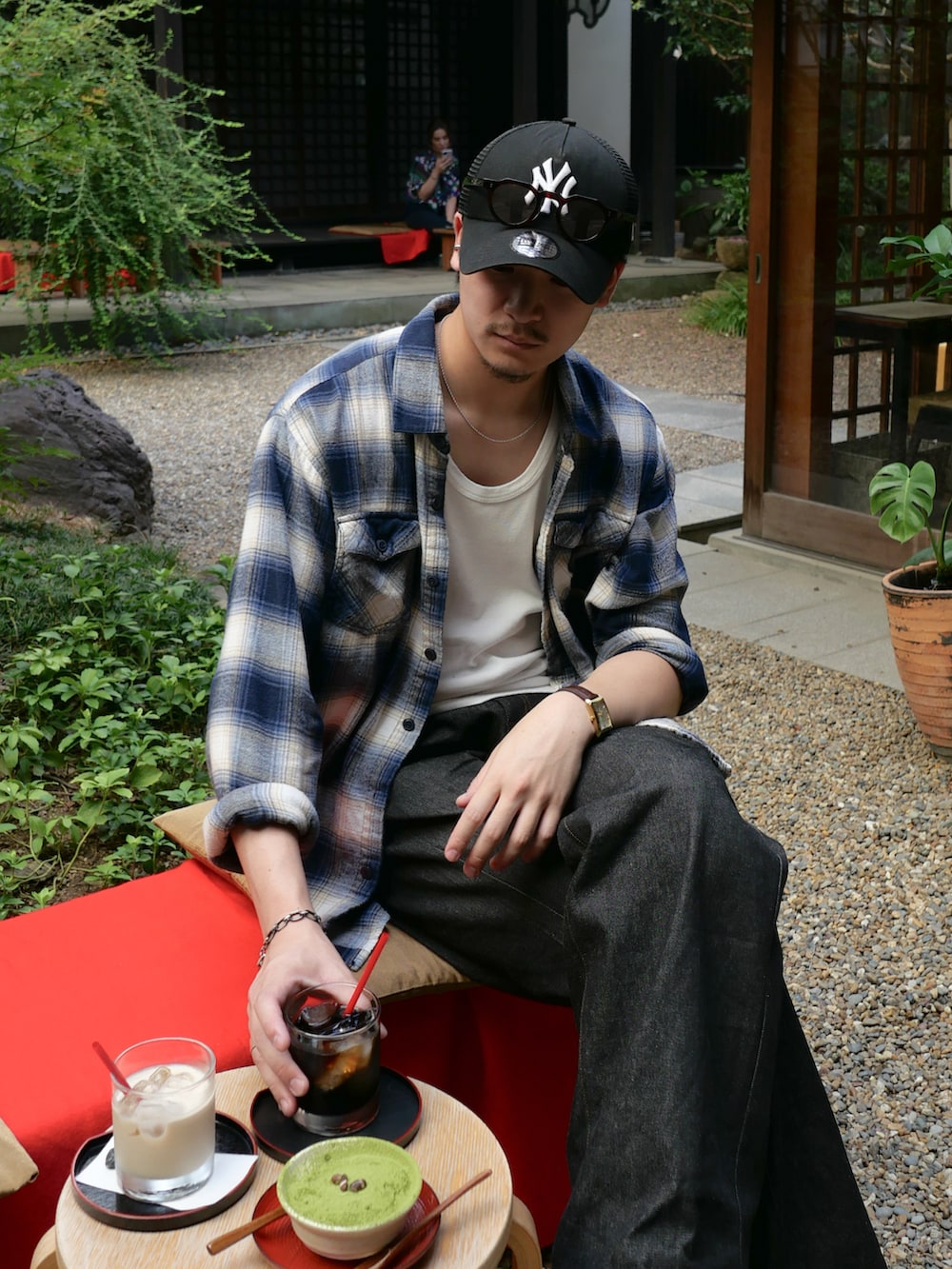 ホワイト系のタンクトップ、ブラック系のデニムパンツ、レッド系のボストンバッグを着用したメンズの秋コーディネートの2枚目の写真