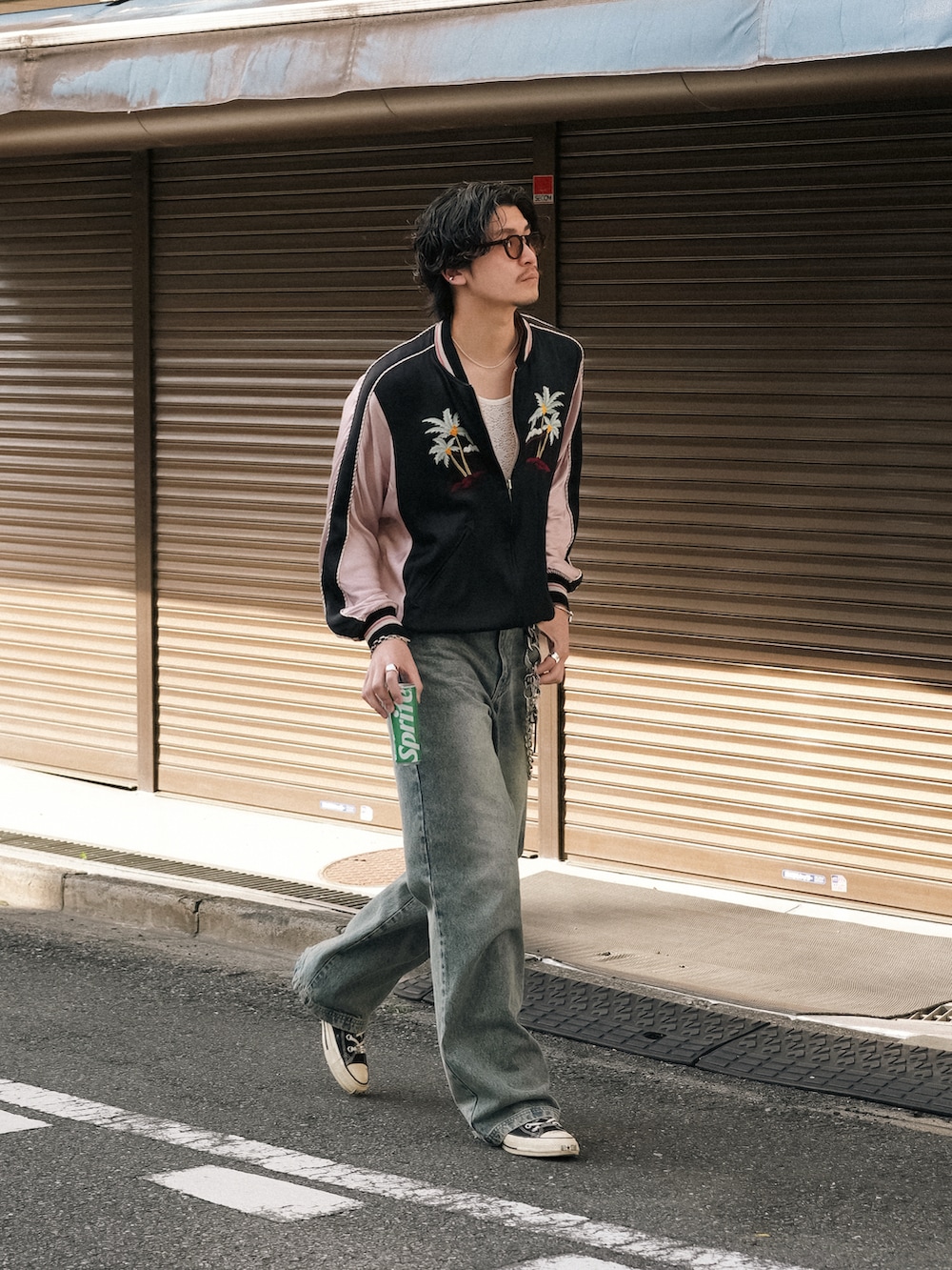 ブルー系のデニムパンツ、ブラック系のスニーカー、ブラック系のスタジャンを着用したメンズの春コーディネートの5枚目の写真