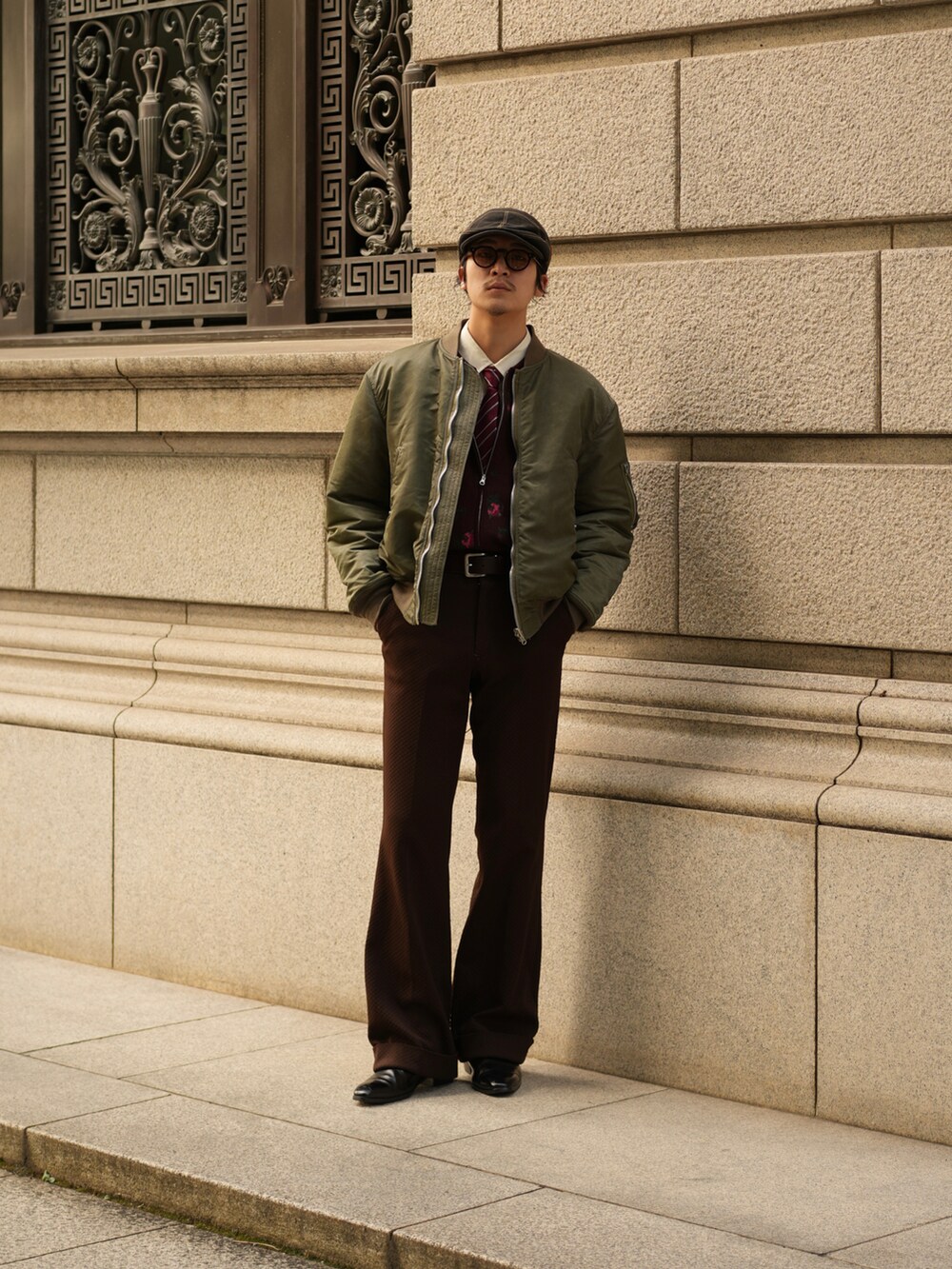 ブラウン系のスラックス、ブラック系のブーツ、グリーン系のMA-1を着用したメンズの秋コーディネートの2枚目の写真