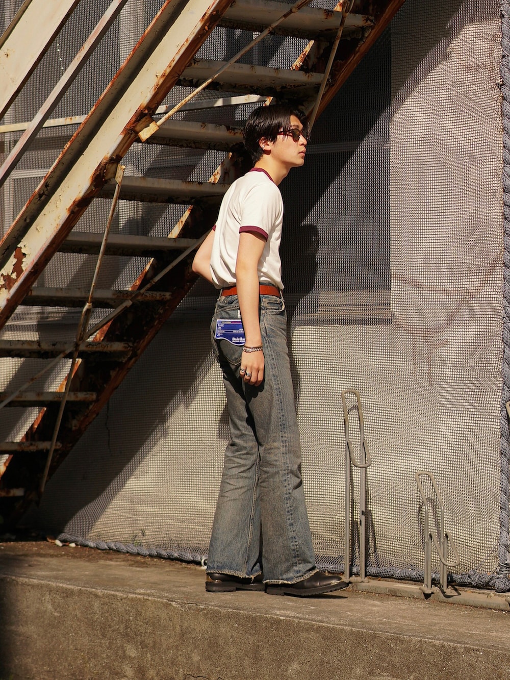 ブルー系のデニムパンツ、ブラック系のブーツ、レッド系のTシャツ/カットソーを着用したメンズの春コーディネートの3枚目の写真