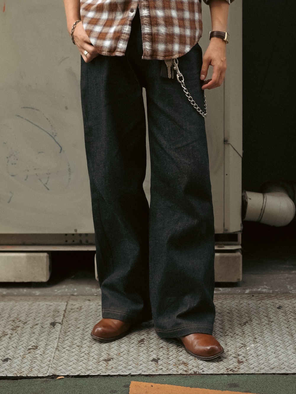 ホワイト系のタンクトップ、ブラック系のデニムパンツ、ブラウン系のブーツを着用したメンズの秋コーディネートの4枚目の写真