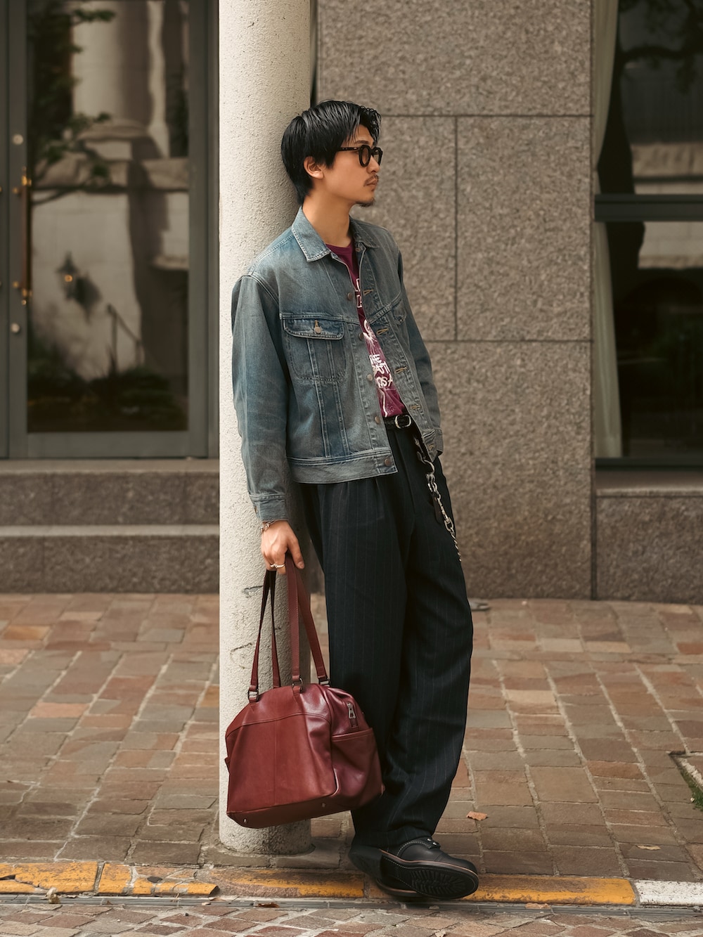 ブルー系のデニムジャケット、レッド系のTシャツ/カットソー、ブラック系のスラックスを着用したメンズの春コーディネートの4枚目の写真