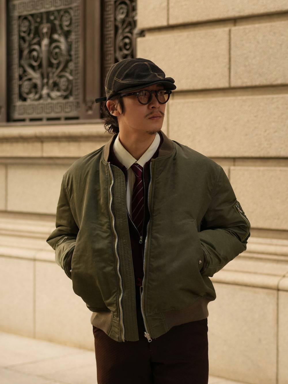 ブラウン系のスラックス、ブラック系のブーツ、グリーン系のMA-1を着用したメンズの秋コーディネートの3枚目の写真