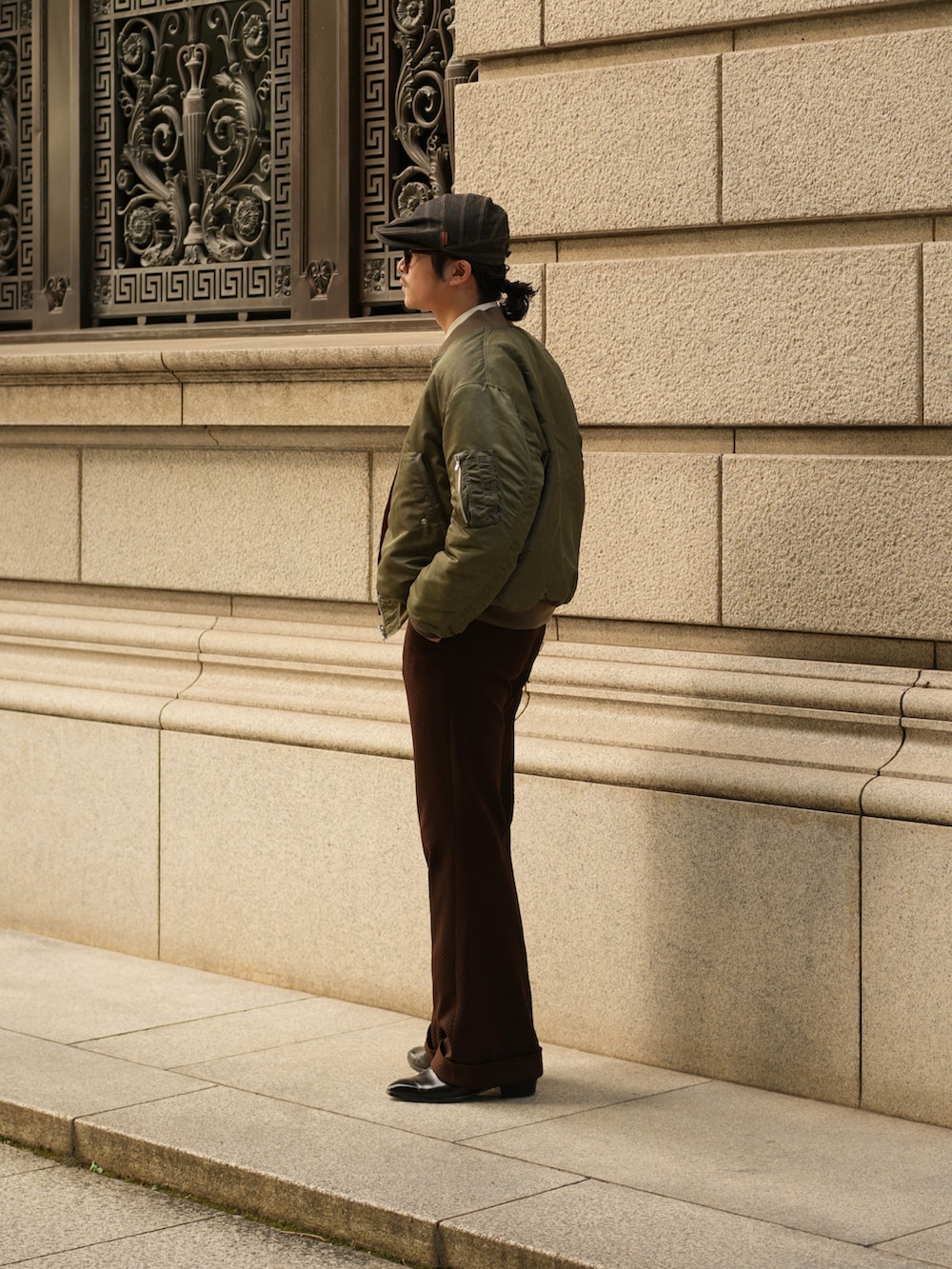 ブラウン系のスラックス、ブラック系のブーツ、グリーン系のMA-1を着用したメンズの秋コーディネートの4枚目の写真