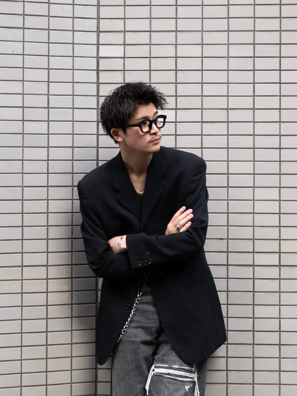 ブラック系のデニムパンツ、ブラック系のテーラードジャケット、ベージュ系のタンクトップを着用したメンズの冬コーディネートの2枚目の写真