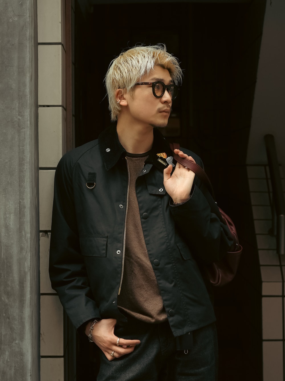 ブラック系のデニムパンツ、ブラウン系のローファー、ブラック系のブルゾンを着用したメンズの春コーディネートの2枚目の写真