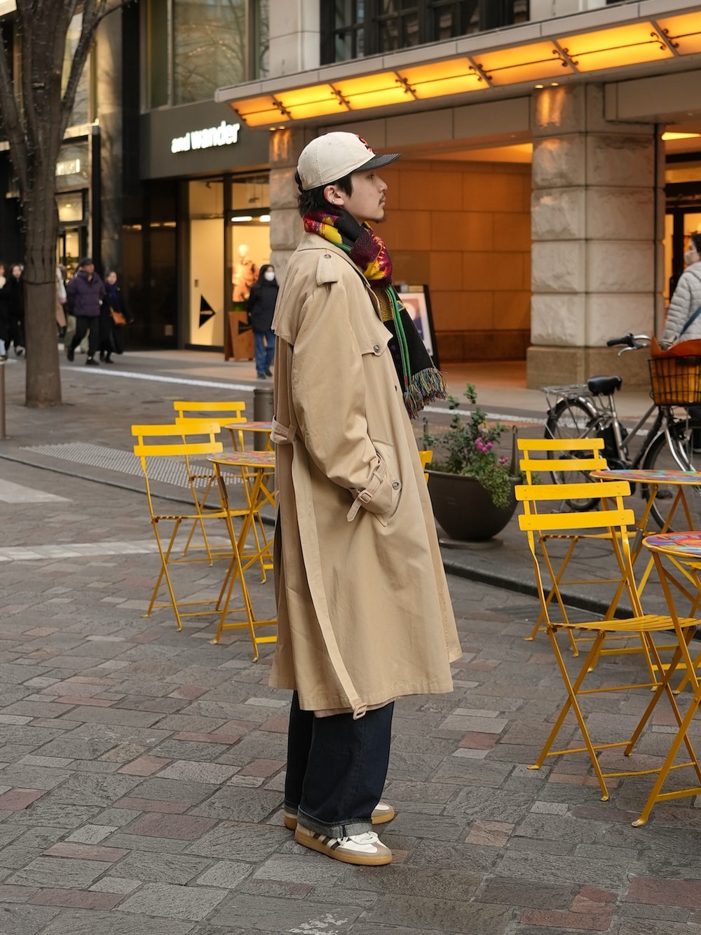 ホワイト系のスニーカー、ブルー系のデニムパンツ、ベージュ系のトレンチコートを着用したメンズの冬コーディネートの3枚目の写真