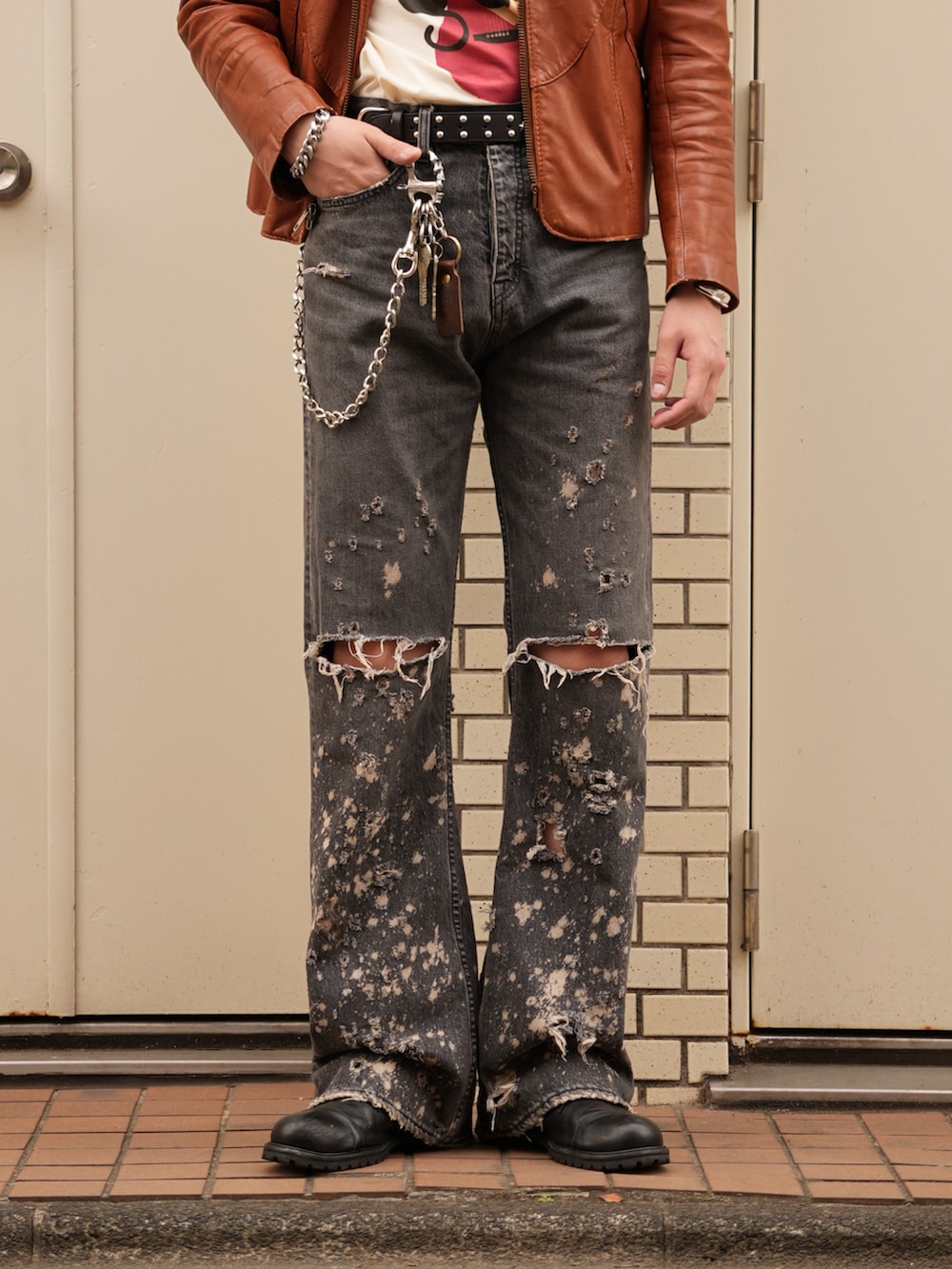 ブラック系のデニムパンツ、ベージュ系のTシャツ/カットソー、オレンジ系のジャケット/アウターを着用したメンズの春コーディネートの4枚目の写真