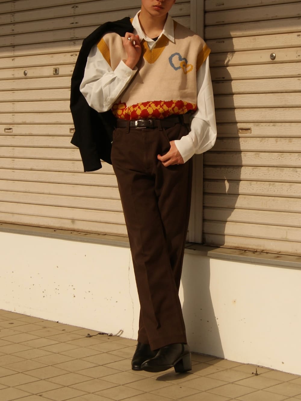 ブラウン系のデニムパンツ、ブラック系のドレスシューズ、イエロー系のベストを着用したメンズの春コーディネートの3枚目の写真