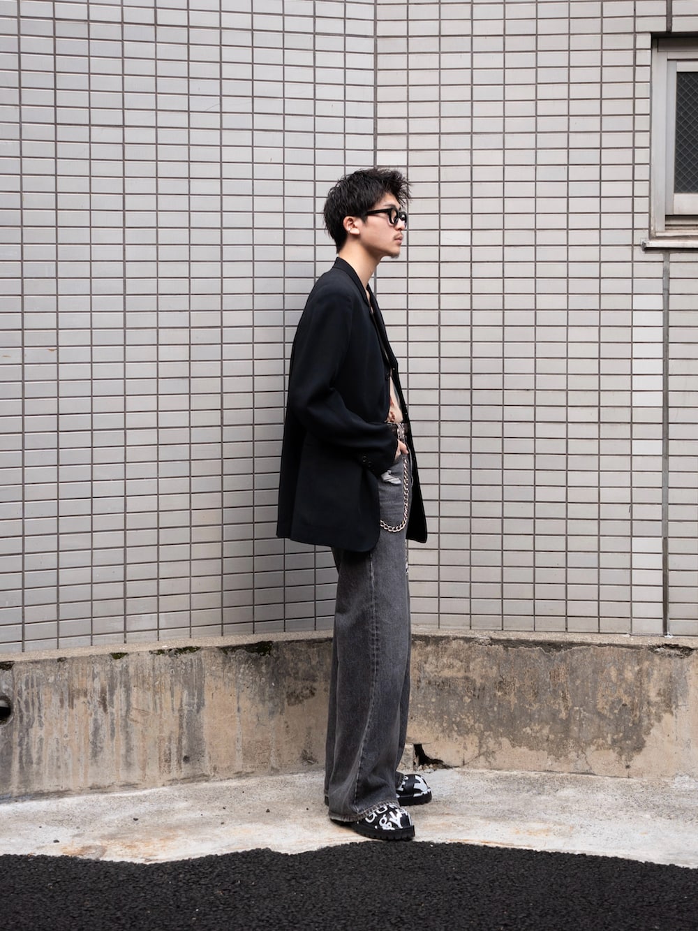 ブラック系のデニムパンツ、ブラック系のテーラードジャケット、ベージュ系のタンクトップを着用したメンズの冬コーディネートの3枚目の写真