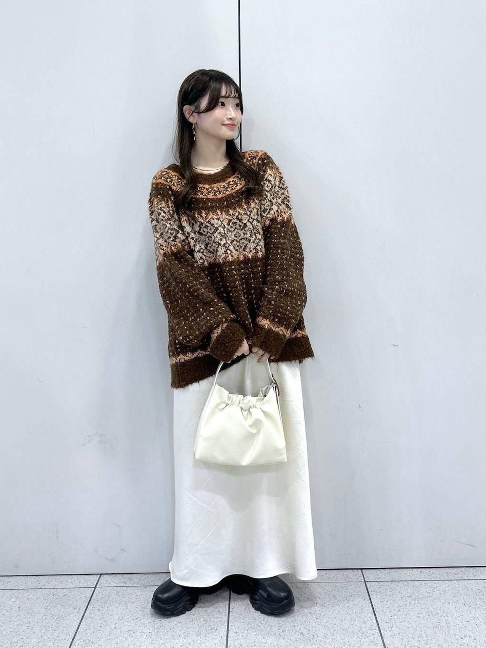 ブラック系のブーツ、ホワイト系のスカート、ホワイト系のショルダーバッグを着用したレディースの冬コーディネートの4枚目の写真