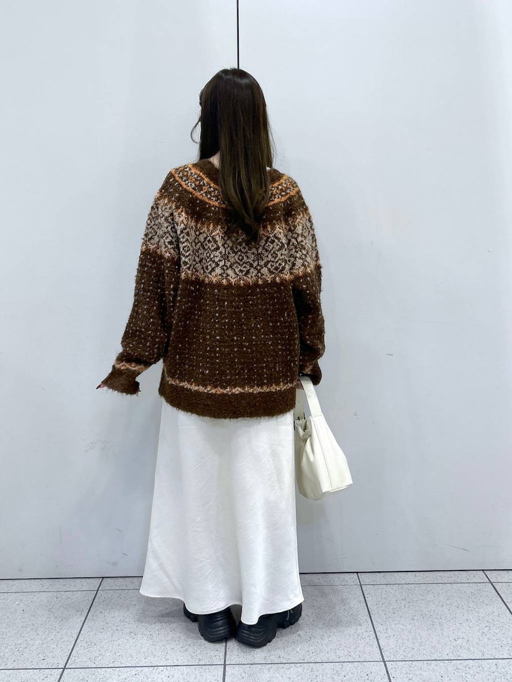 ブラック系のブーツ、ホワイト系のスカート、ホワイト系のショルダーバッグを着用したレディースの冬コーディネートの3枚目の写真