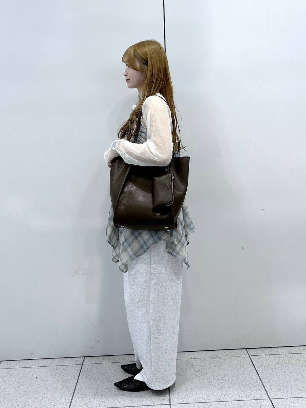 グレー系のスウェットパンツ、ブラック系のパンプス、ブラウン系のトートバッグを着用したレディースの春コーディネートの2枚目の写真