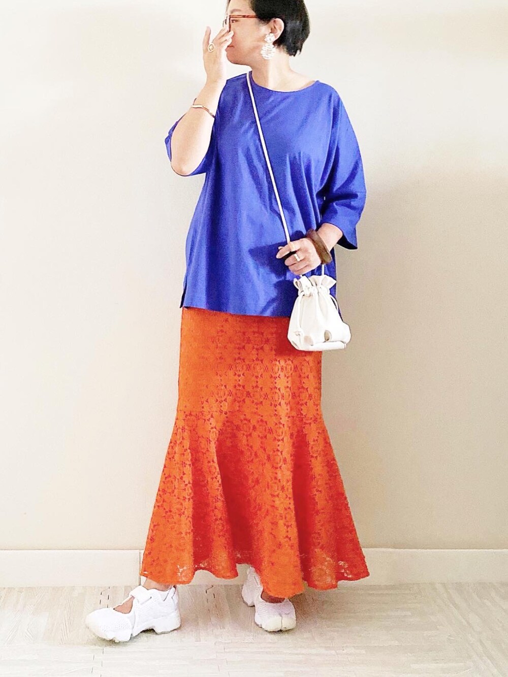 ブルー系のトップス、オレンジ系のスカート、ベージュ系のショルダーバッグを着用したレディースの夏コーディネートの2枚目の写真