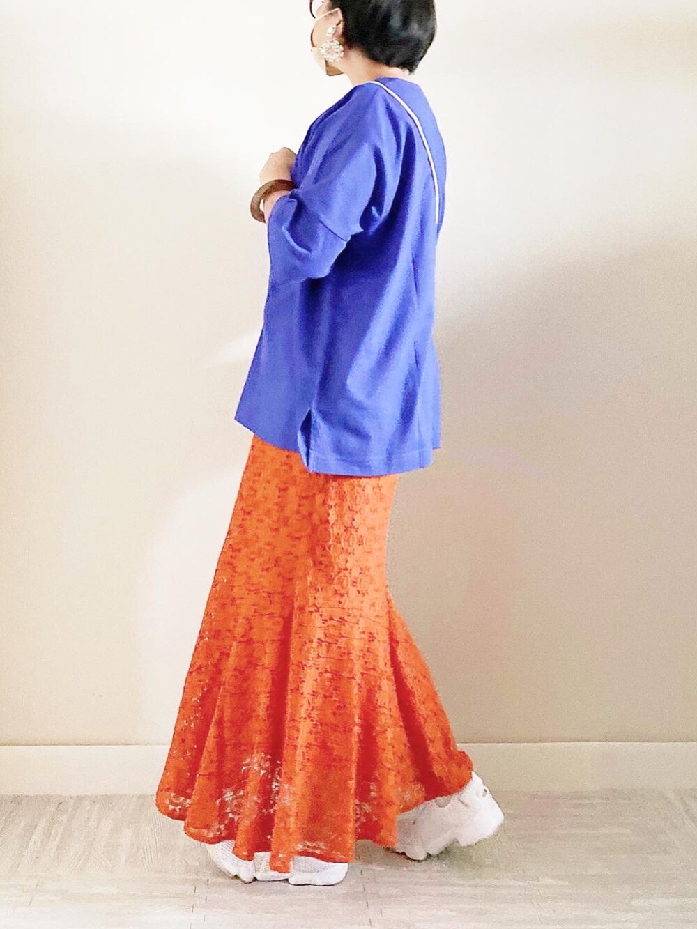 ブルー系のトップス、オレンジ系のスカート、ベージュ系のショルダーバッグを着用したレディースの夏コーディネートの3枚目の写真