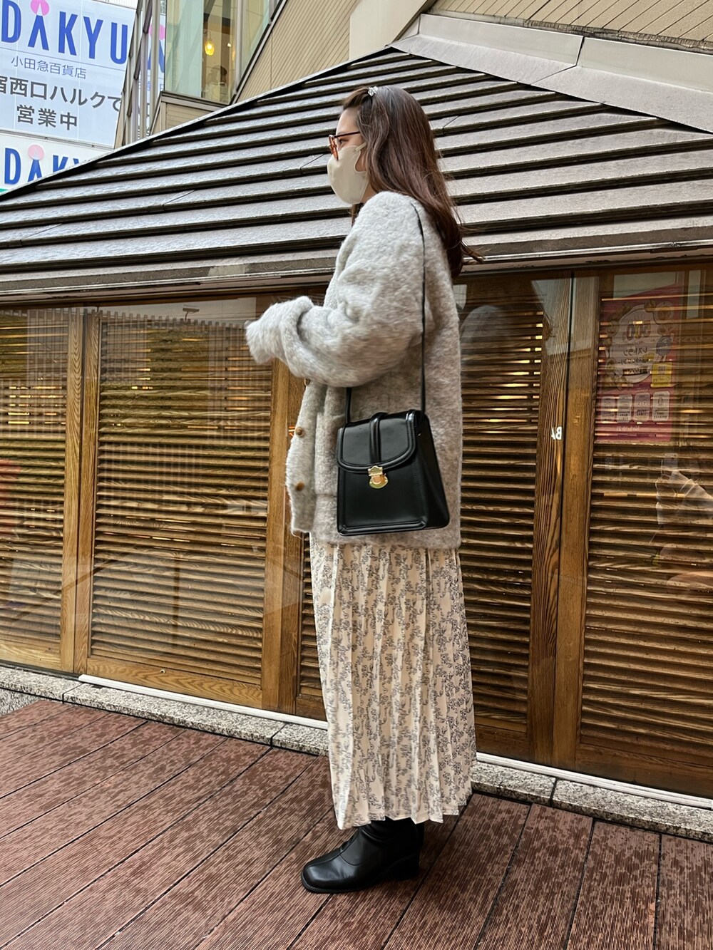 ホワイト系のワンピース、グレー系のカーディガン/ボレロ、ブラック系のショルダーバッグを着用したレディースの秋コーディネートの2枚目の写真