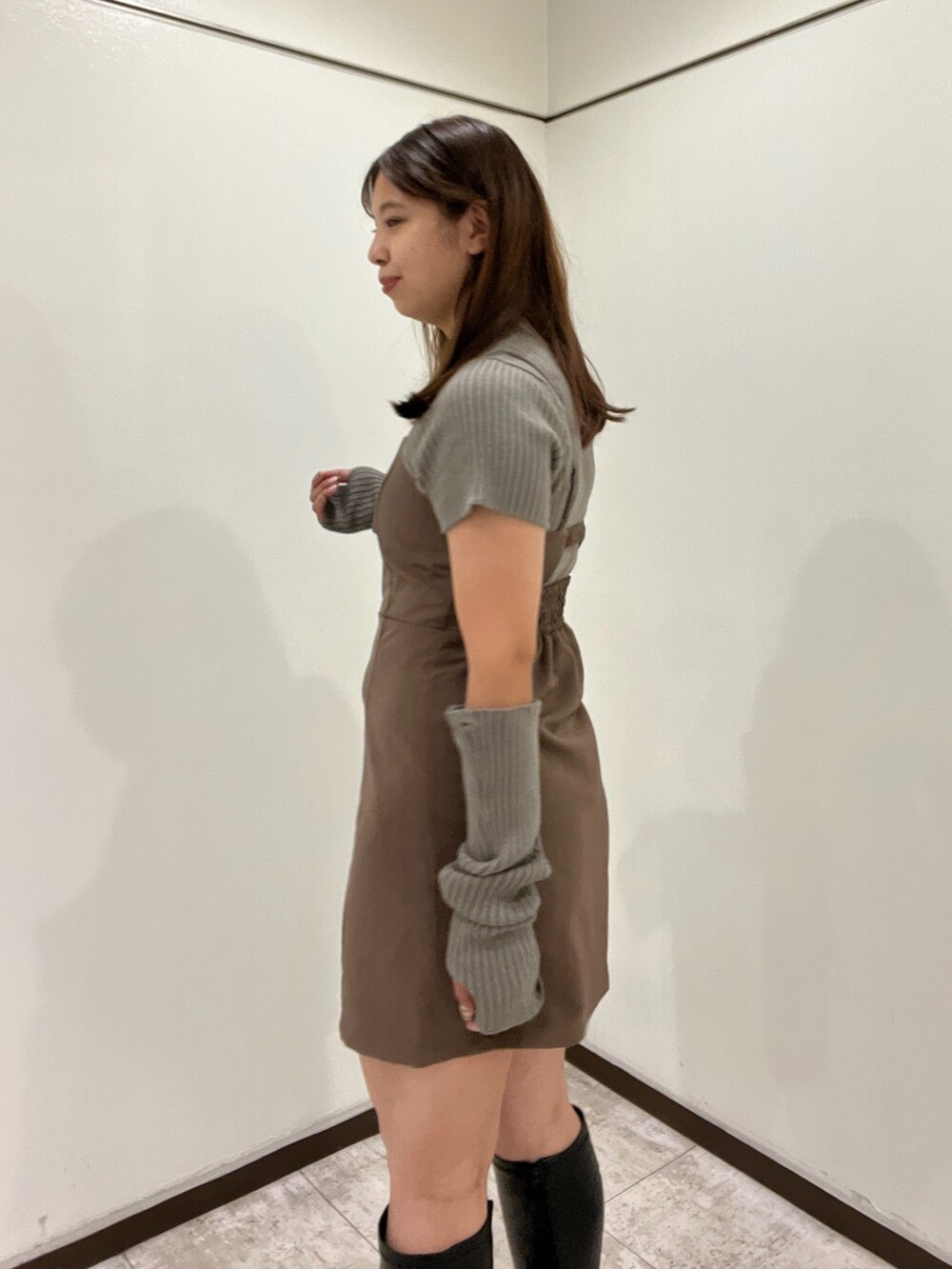 グリーン系のニット/セーター、ブラウン系のワンピース、ブラウン系のボストンバッグを着用したレディースの秋コーディネートの2枚目の写真