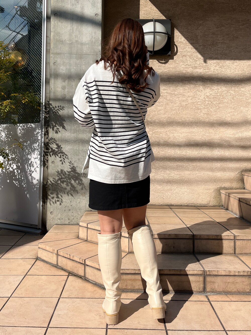 ブラック系のTシャツ/カットソー、ホワイト系のショルダーバッグ、ブラック系のスカートを着用したレディースの冬コーディネートの3枚目の写真