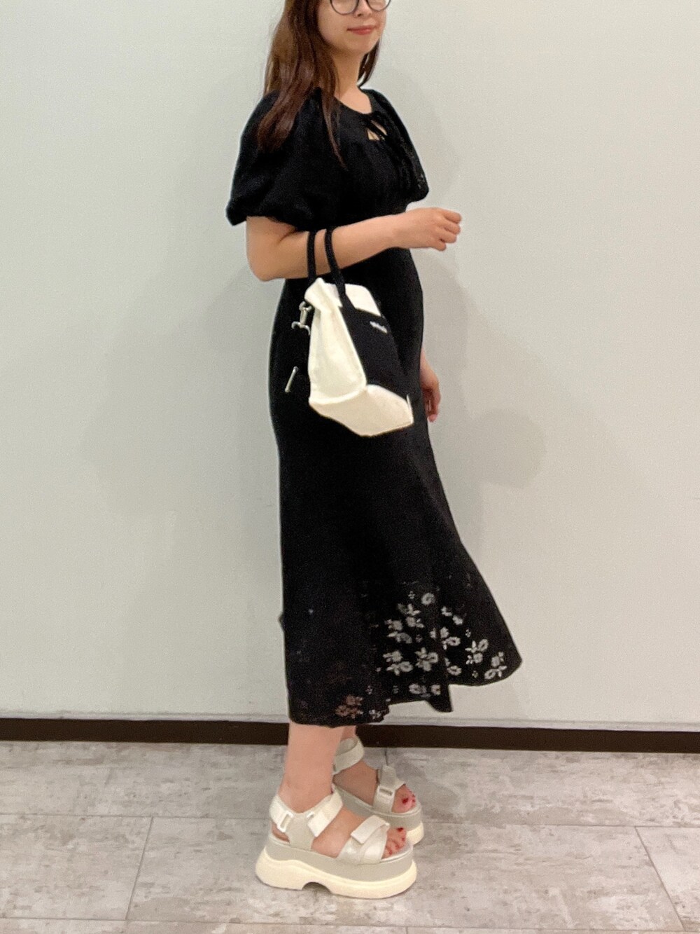 ブラック系のワンピース、ブラック系のショルダーバッグ、ホワイト系のサンダルを着用したレディースの春コーディネートの2枚目の写真