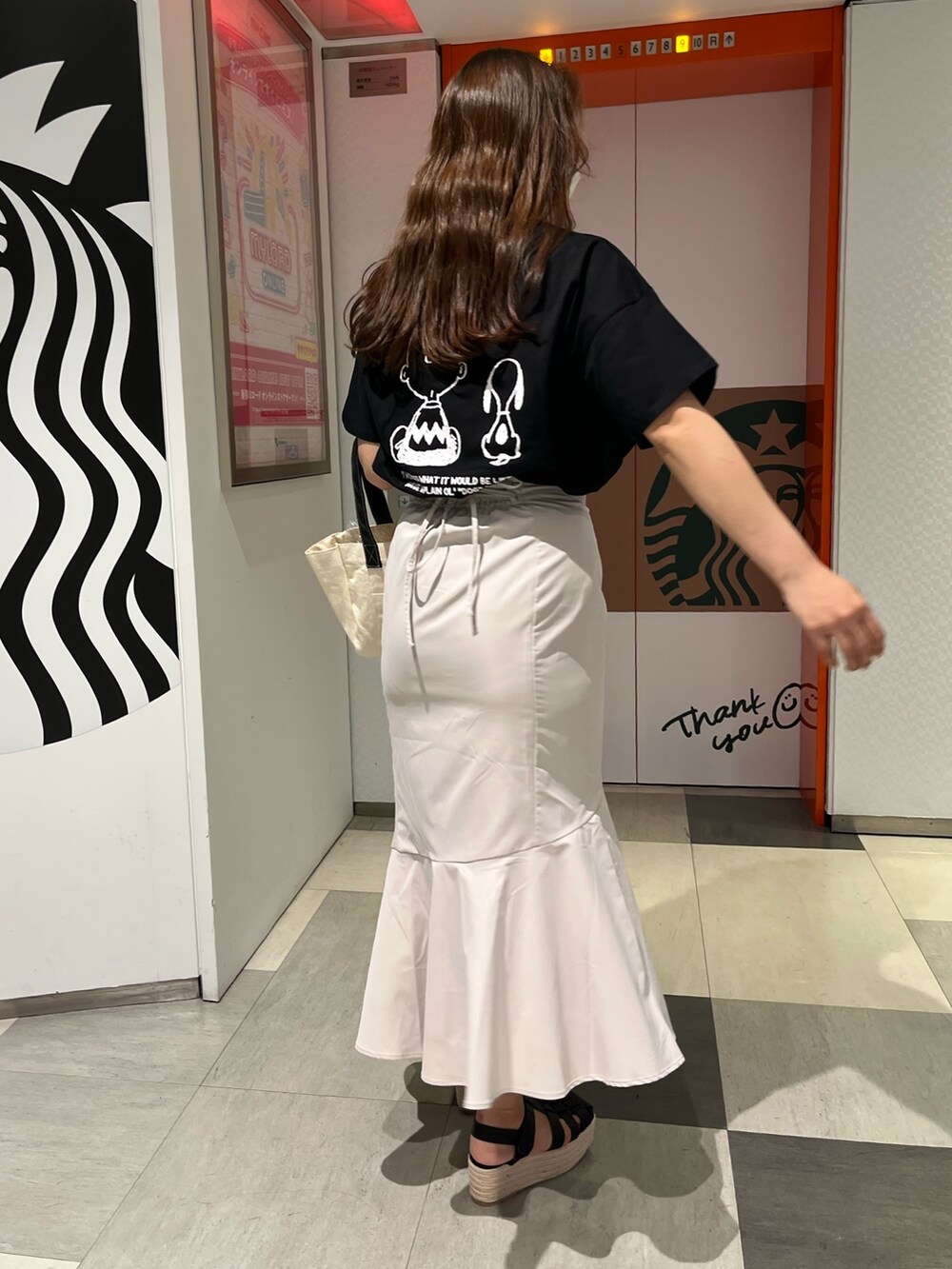 ブラック系のTシャツ/カットソー、ホワイト系のトートバッグ、ホワイト系のスカートを着用したレディースの春コーディネートの2枚目の写真