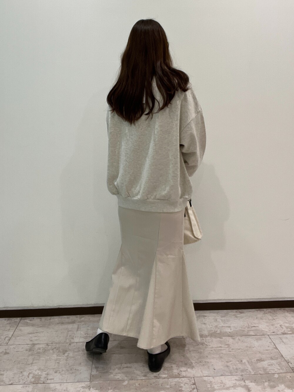 グレー系のスウェット、ホワイト系のスカート、ブラック系のショルダーバッグを着用したレディースの春コーディネートの3枚目の写真