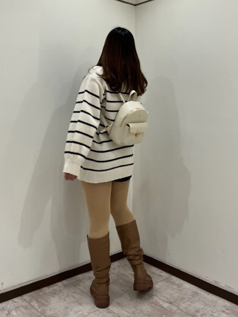 イエロー系のブーツ、ホワイト系のニット/セーター、ホワイト系のバックパック/リュックを着用したレディースの冬コーディネートの2枚目の写真