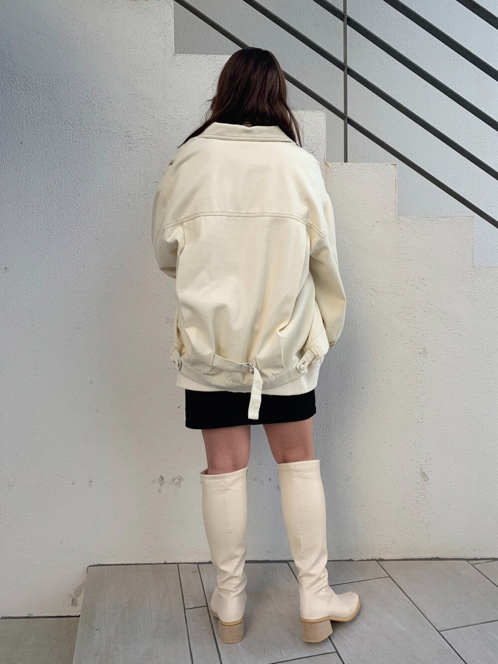 ホワイト系のデニムジャケット、ホワイト系のブーツ、ホワイト系のショルダーバッグを着用したレディースの冬コーディネートの2枚目の写真