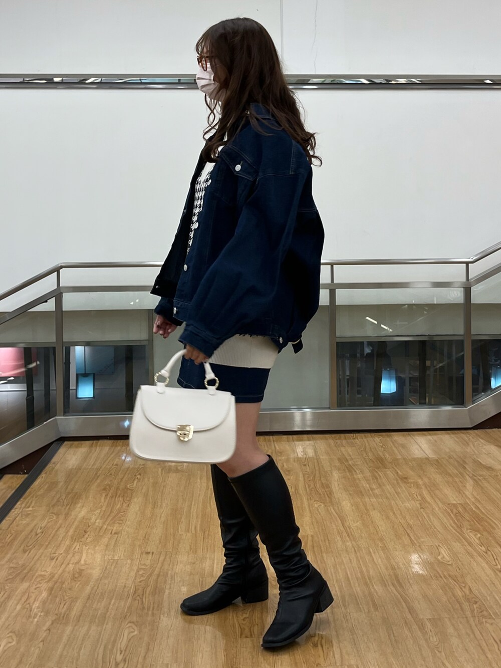 ブルー系のデニムジャケット、ホワイト系のベスト、ホワイト系のショルダーバッグを着用したレディースの冬コーディネートの2枚目の写真