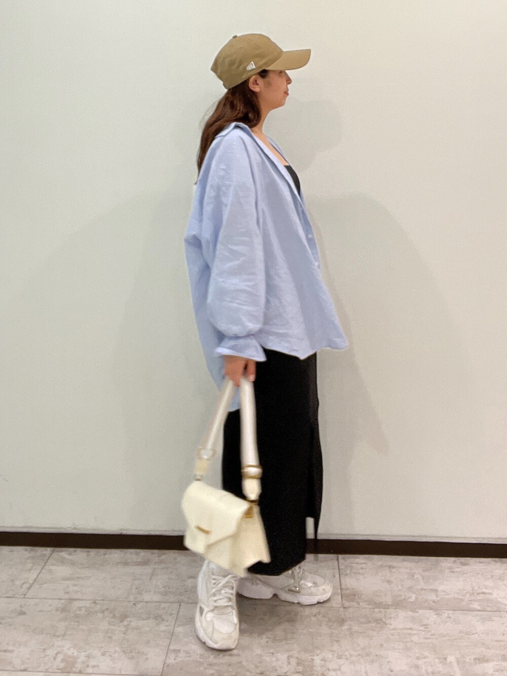 ブルー系のシャツ/ブラウス、ブラック系のジャンパースカート、ホワイト系のショルダーバッグを着用したレディースの春コーディネートの4枚目の写真