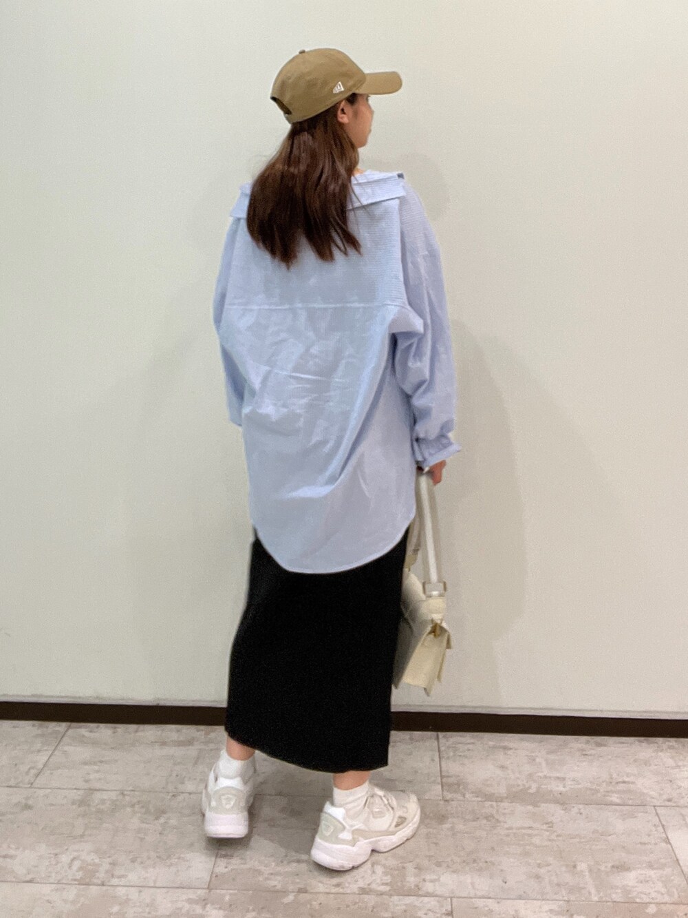 ブルー系のシャツ/ブラウス、ブラック系のジャンパースカート、ホワイト系のショルダーバッグを着用したレディースの春コーディネートの3枚目の写真