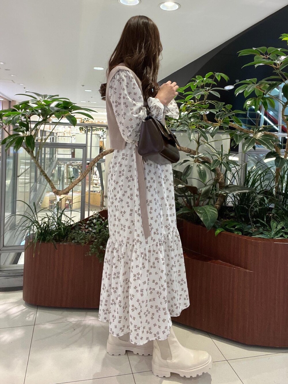 ベージュ系のワンピース、ブラウン系のショルダーバッグ、ホワイト系のブーツを着用したレディースの冬コーディネートの2枚目の写真