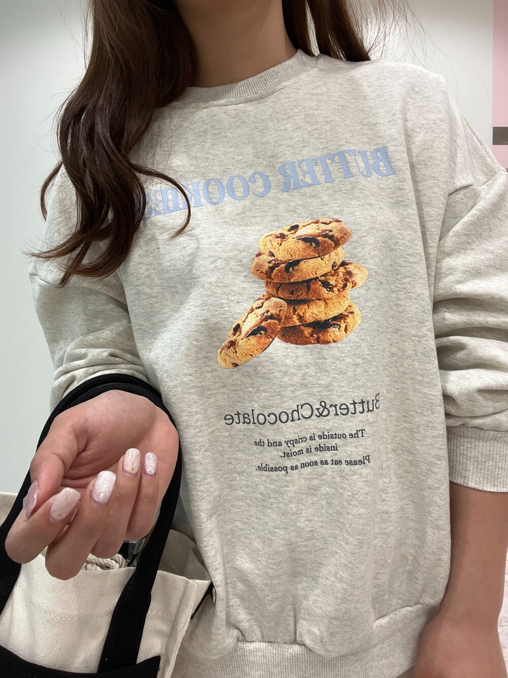 グレー系のスウェット、ホワイト系のスカート、ブラック系のショルダーバッグを着用したレディースの春コーディネートの4枚目の写真