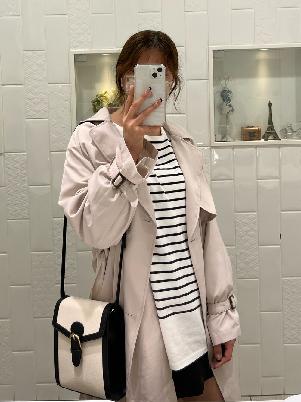 ブラック系のTシャツ/カットソー、ベージュ系のトレンチコート、ブラック系のショルダーバッグを着用したレディースの冬コーディネートの2枚目の写真