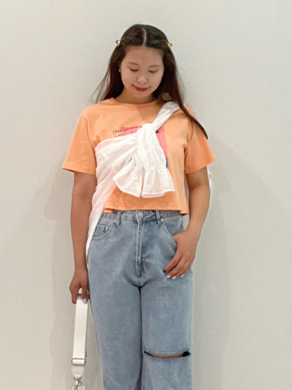 オレンジ系のTシャツ/カットソー、ホワイト系のシャツ/ブラウス、ブルー系のデニムパンツを着用したレディースの夏コーディネートの4枚目の写真