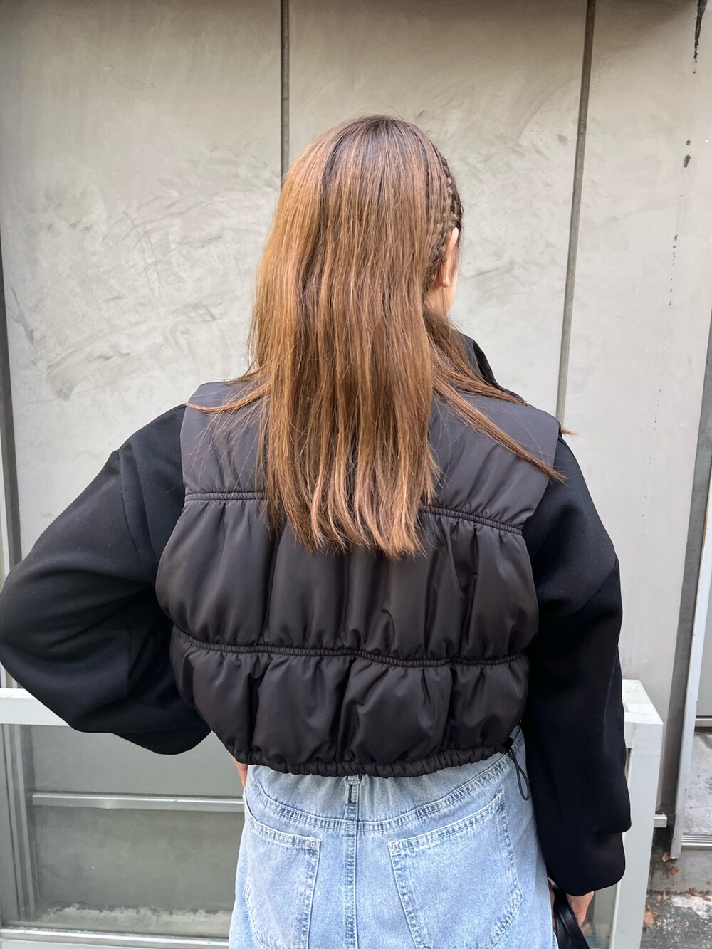 ブラック系のダウンベスト、ブラック系のTシャツ/カットソー、ブルー系のカーゴパンツを着用したレディースの秋コーディネートの3枚目の写真