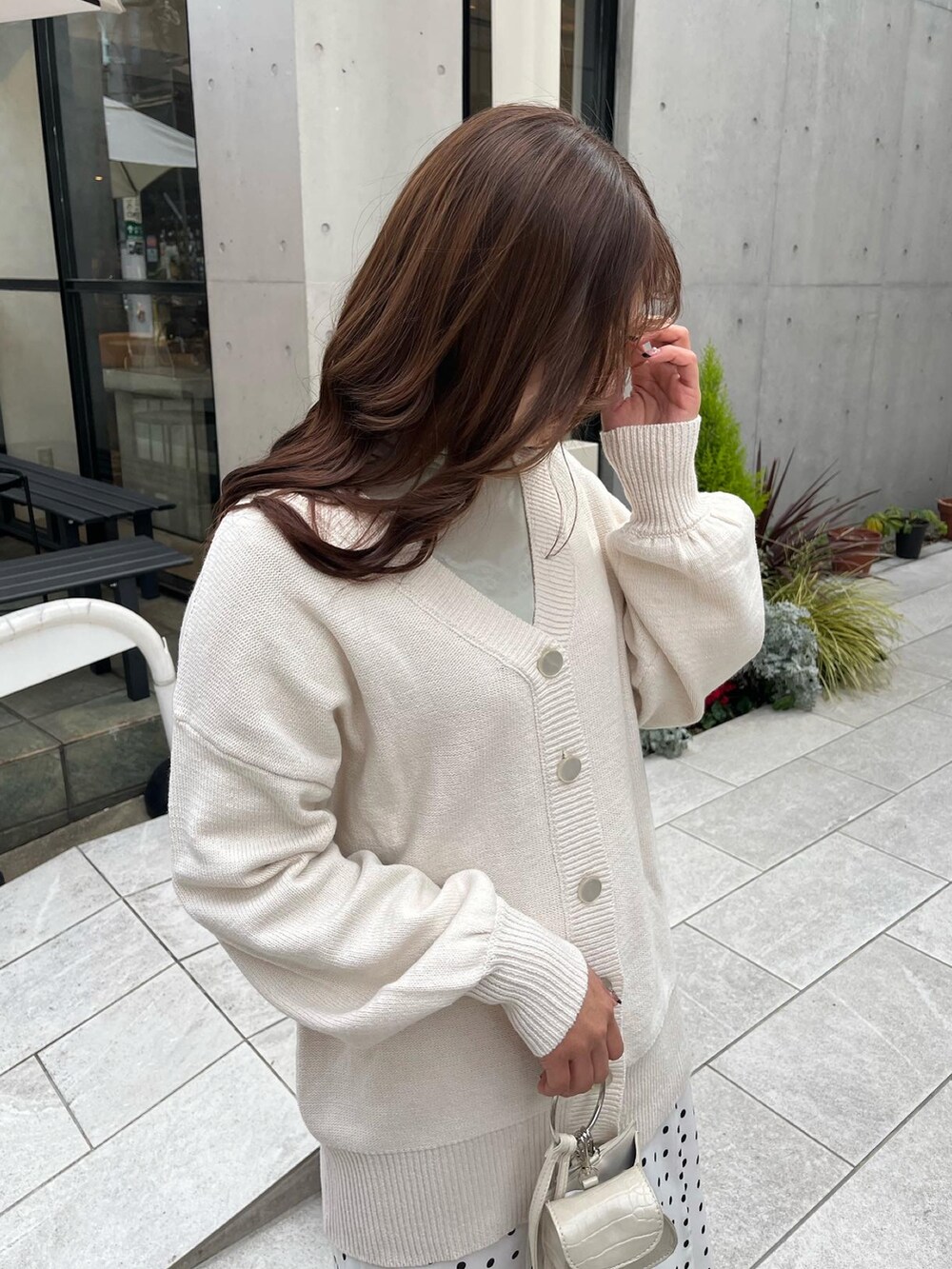 グリーン系のTシャツ/カットソー、ホワイト系のカーディガン/ボレロ、ホワイト系のショルダーバッグを着用したレディースの冬コーディネートの4枚目の写真