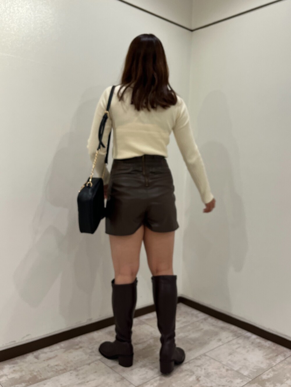 ホワイト系のニット/セーター、ブラウン系のスカート、ブラック系のショルダーバッグを着用したレディースの秋コーディネートの2枚目の写真